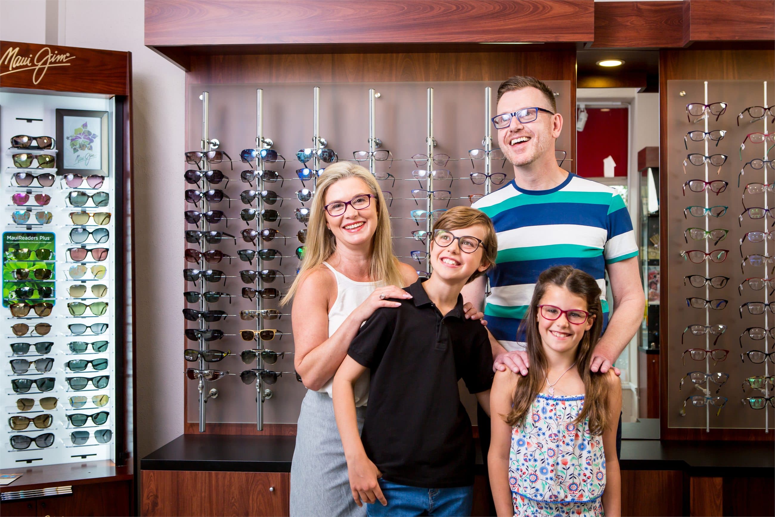 Ashburton Eyecare family standing beside the eyewear display