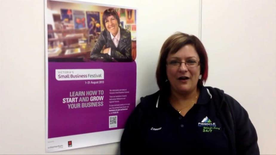 A workshop participant standing beside a Victoria's Small Business Festival poster at a Melbourne social media marketing training session